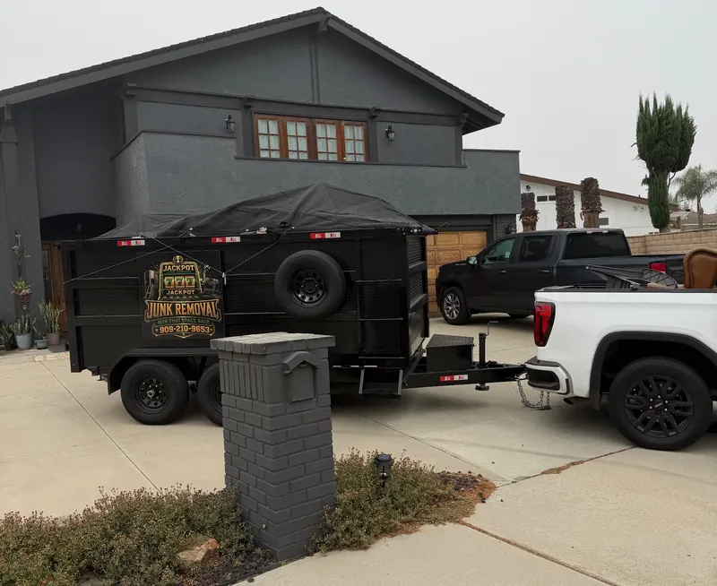 Jackpot Junk Removal trailer parked in a customer’s driveway, loaded and tarped